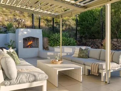 a patio with two couches and a fireplace at Phezulu Manor, Panoramic Views, Serviced Retreat in Gordonʼs Bay