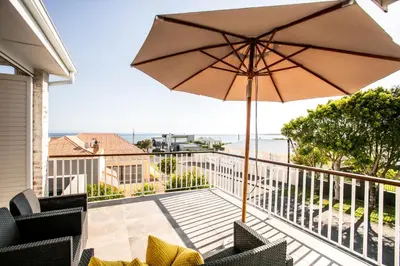 a patio with an umbrella and chairs on a balcony at Sur La Mer in Hermanus