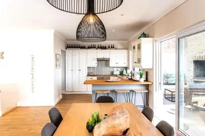 a kitchen with a wooden table and a dining room at Sur La Mer in Hermanus