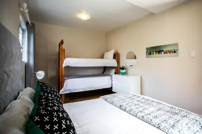 a bedroom with two beds and a bunk bed at Sur La Mer in Hermanus