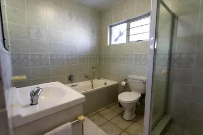 a bathroom with a sink and a toilet and a tub at Sur La Mer in Hermanus