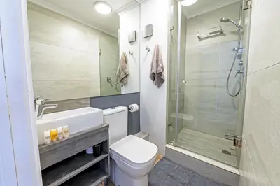 a bathroom with a toilet and a glass shower at Luxury Beachfront Apartment in Blouberg, 304 The Waves in Bloubergstrand
