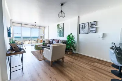 a living room with a couch and a table at Luxury Beachfront Apartment in Blouberg, 304 The Waves in Bloubergstrand