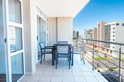 a balcony with a table and chairs on a building at Luxury Beachfront Apartment in Blouberg, 304 The Waves in Bloubergstrand