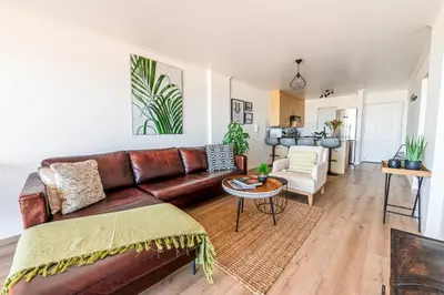 a living room with a brown leather couch at Luxury Beachfront Apartment in Blouberg, 304 The Waves in Bloubergstrand
