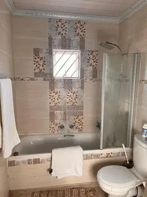 a bathroom with a tub and a toilet and a window at Self catering three bedroom in Cape Town