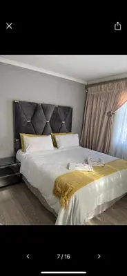 a bedroom with a large white bed with a headboard at Self catering three bedroom in Cape Town