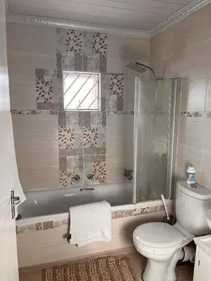 a bathroom with a toilet and a shower and a sink at Self catering three bedroom in Cape Town