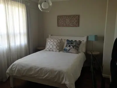 a bedroom with a white bed and a window at Beachfront Apartment at Seaspray in Blouberg in Bloubergstrand
