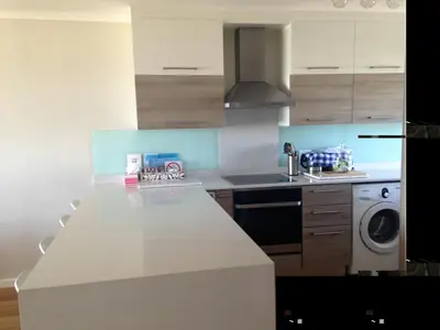 a kitchen with a white counter and a washing machine at Beachfront Apartment at Seaspray in Blouberg in Bloubergstrand