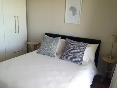 a bedroom with a white bed with two blue pillows at Beachfront Apartment at Seaspray in Blouberg in Bloubergstrand