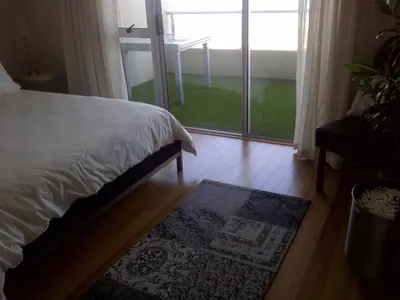a bedroom with a bed and a large window at Beachfront Apartment at Seaspray in Blouberg in Bloubergstrand