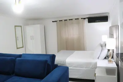 a hotel room with a bed and a blue couch at Optimum Stay Self Catering Accommodation - Deluxe Room in Cape Town