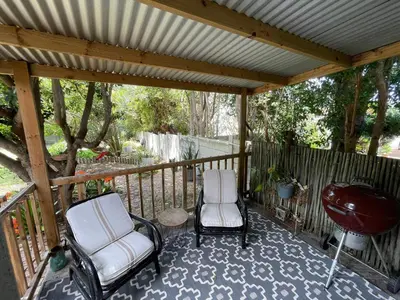 a porch with two chairs and a grill and a grill at Mosselberg Garden Gottage in Hermanus