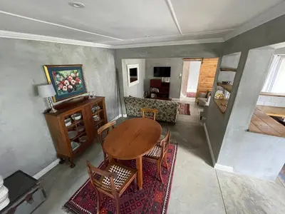 a living room with a wooden table and chairs at Mosselberg Garden Gottage in Hermanus