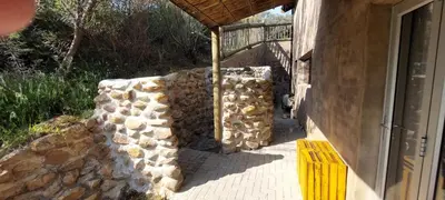 a pile of fire wood next to a stone wall at Riverbank in Tulbagh