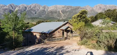 an old barn with mountains in the background at Riverbank in Tulbagh