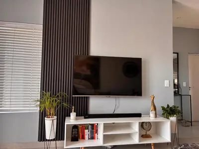 a living room with a flat screen tv on a wall at Modern 3 bedroom Urban Getaway in Cape Town
