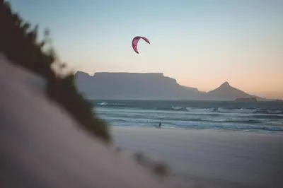 a person is flying a kite on the beach at Coastal Beach & Mountain Retreat in Cape Town