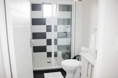 a white bathroom with a toilet and a shower at Coastal Beach & Mountain Retreat in Cape Town