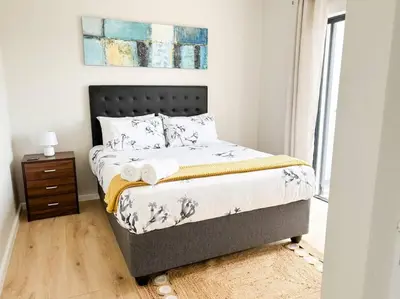 a bedroom with a bed and a dresser and a window at Coastal Beach & Mountain Retreat in Cape Town