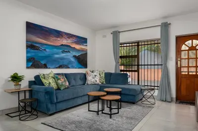 a living room with a blue couch and a window at Tafelzicht Peaceful Retreat - Wifi - Netflix in Cape Town