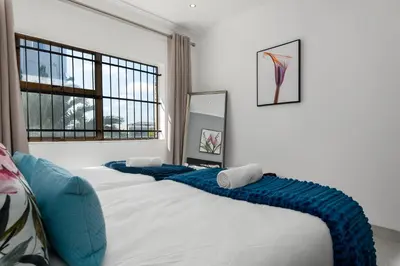a bedroom with two beds with blue pillows on them at Tafelzicht Peaceful Retreat - Wifi - Netflix in Cape Town