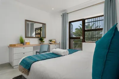 a bedroom with a bed and a desk and a window at Tafelzicht Peaceful Retreat - Wifi - Netflix in Cape Town