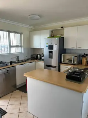 a kitchen with white cabinets and stainless steel appliances at Nautica by the Beach in Cape Town