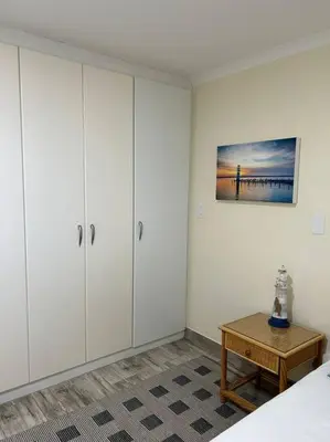 a bedroom with white cabinets and a wooden table at Nautica by the Beach in Cape Town