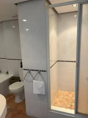 a bathroom with a toilet and a shower with a glass door at Nautica by the Beach in Cape Town