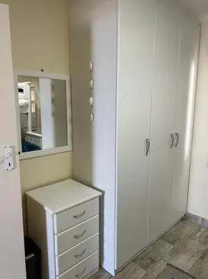 a bedroom with a white cabinet and a mirror at Nautica by the Beach in Cape Town