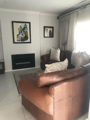 a living room with a brown leather couch and a fireplace at Five bedrooms holiday home in Cape Town