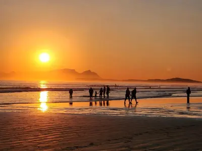 a group of people walking on the beach at sunset at No 4 Life at Sea in Strand