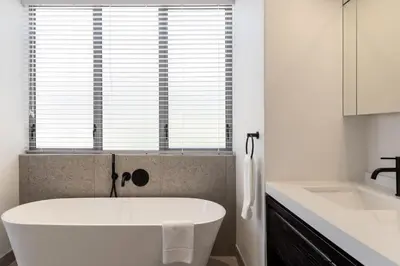 a white bath tub in a bathroom with a window at Azure Retreat in Hermanus