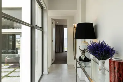 a hallway with a table with a lamp and flowers at Azure Retreat in Hermanus