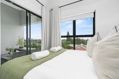 a bedroom with a white bed with a large window at Atlantic Port 10 by Host Agents in Cape Town