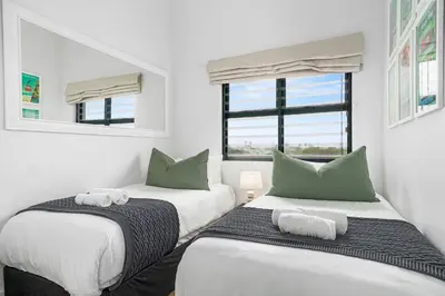 two beds in a room with two windows at Atlantic Port 10 by Host Agents in Cape Town