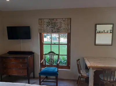 a bedroom with a desk and a window and a table at Klein La Cotte Garden Cottage in Franschhoek