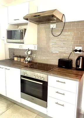 a kitchen with a stove and a microwave at Pinelands guesthouse in Cape Town