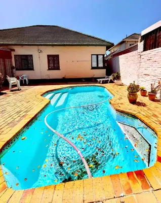 a swimming pool with a hose in front of a house at Pinelands guesthouse in Cape Town