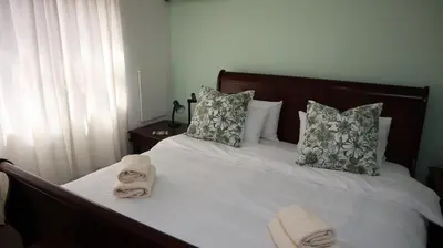 a bedroom with a bed with towels on it at Strand Beach Townhouse Self Catering in Cape Town