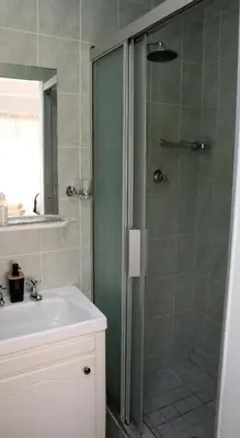 a bathroom with a shower and a sink at Strand Beach Townhouse Self Catering in Cape Town