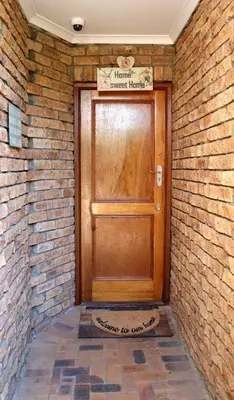 a wooden door in a brick wall with a sign on it at Strand Beach Townhouse Self Catering in Cape Town