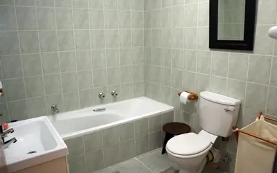 a bathroom with a toilet and a tub and a sink at Strand Beach Townhouse Self Catering in Cape Town