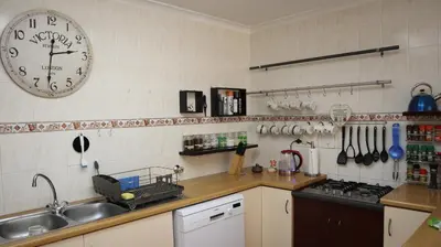 a kitchen with a sink and a clock on the wall at Strand Beach Townhouse Self Catering in Cape Town