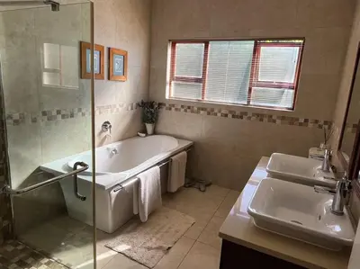 a bathroom with a tub and two sinks and a shower at Divine View in Cape Town