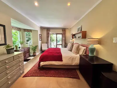 a bedroom with a large bed with a red rug at Garden oasis in the village in Franschhoek
