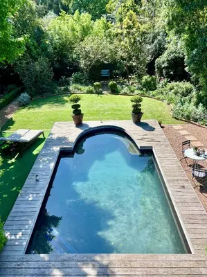 a swimming pool in a garden with a table and chairs at Garden oasis in the village in Franschhoek