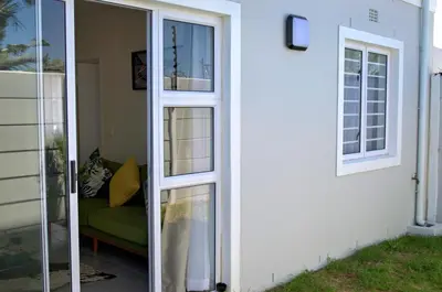 a sliding glass door with a couch next to a house at Camden Stay - Entire Unit - Cape Town in Cape Town